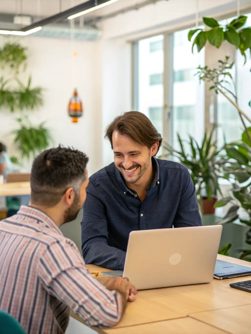 A photo of a software developer at IntraTech Inc. in a casual office setting, smiling and engaged in a video call with a client, discussing project progress and requirements.